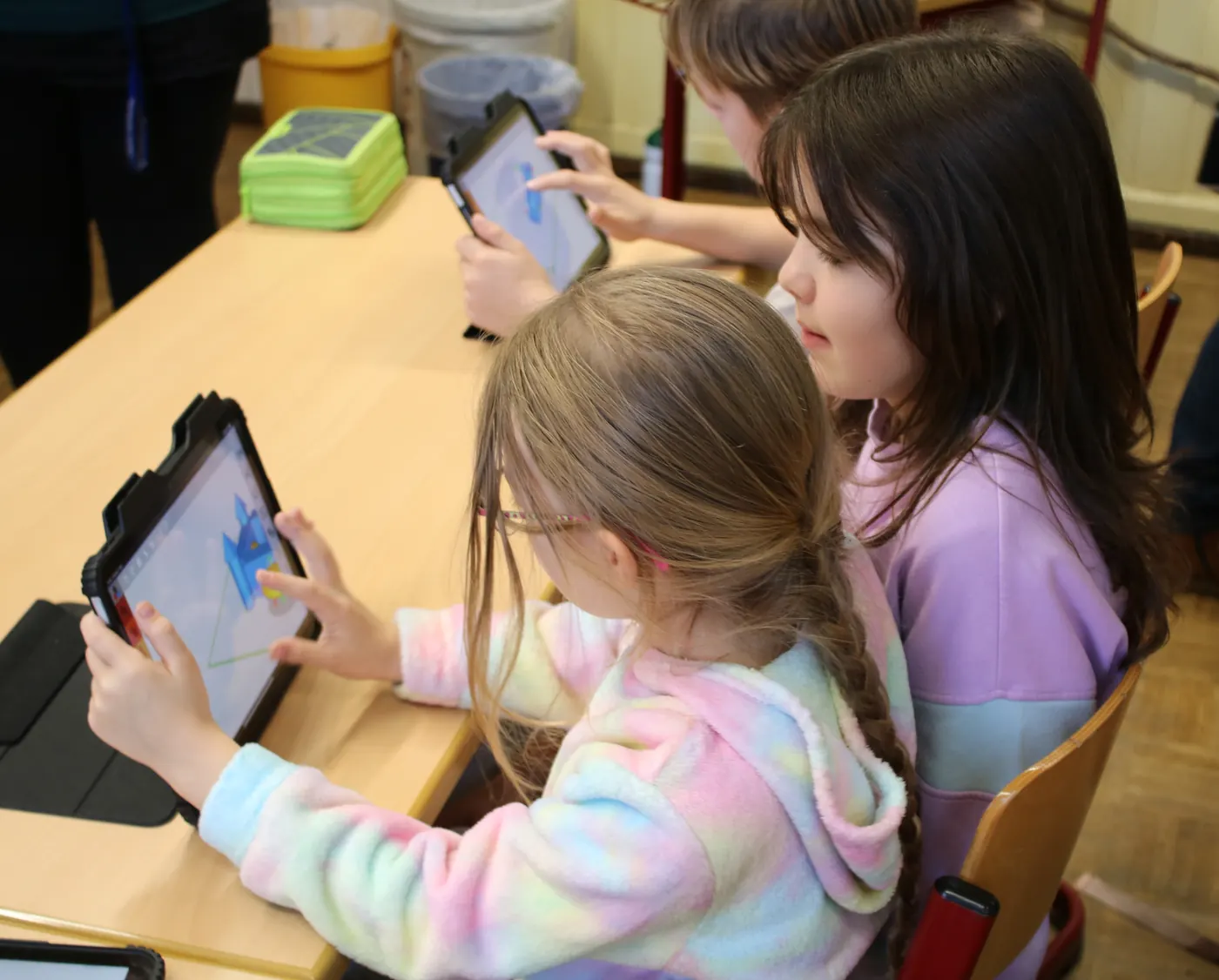 Zwei Grundschülerinnen konstruieren nebeneinander am Tablet ein Modell aus Grundformen